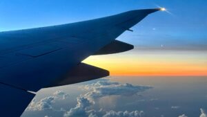 An airplane wing flying over the clouds during a sunset