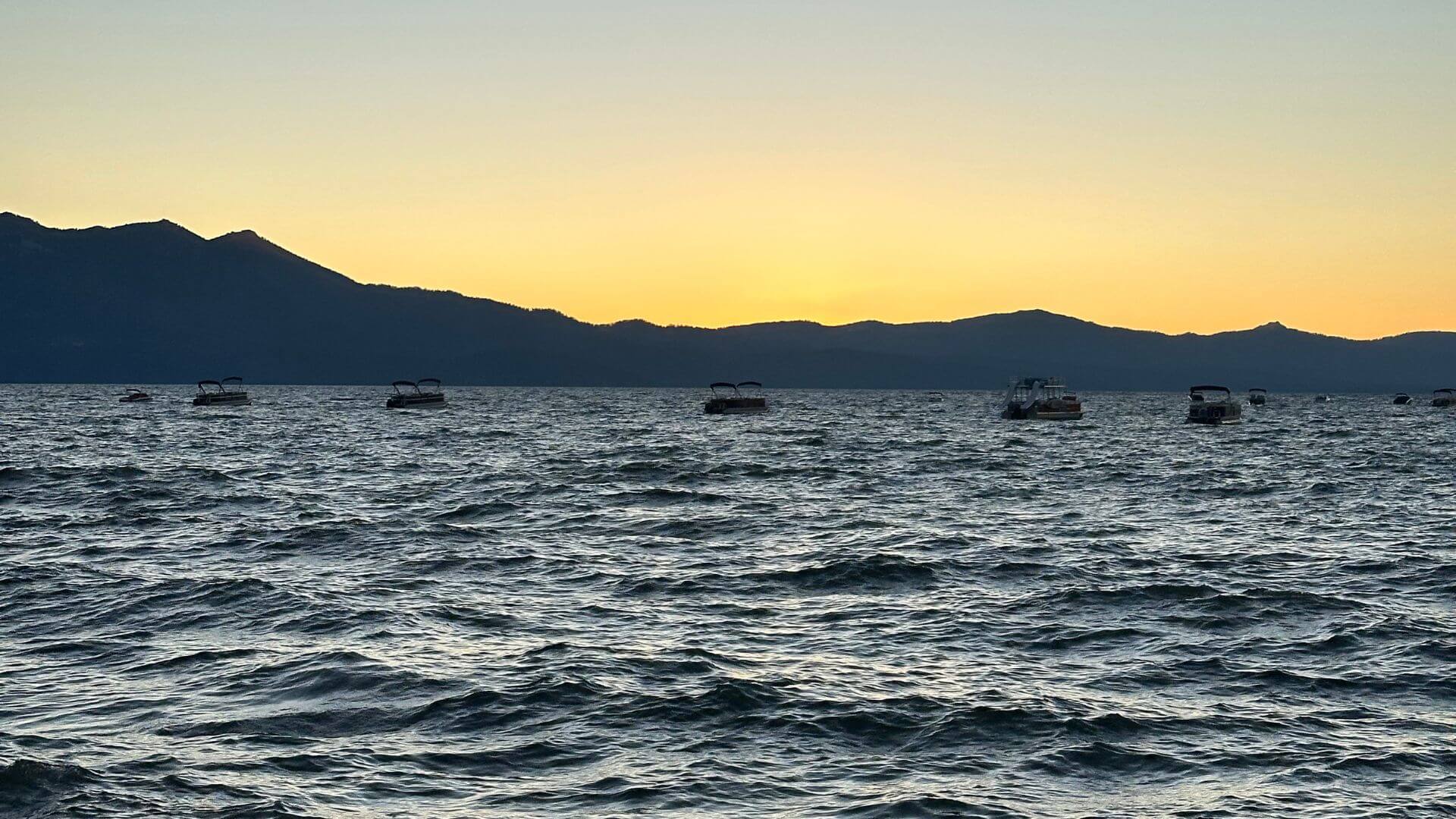 Lake Tahoe sunset with boats out on the lake and mountains in the background